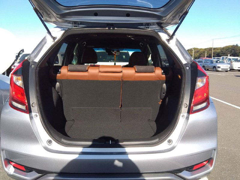 Багажное отделение Honda Fit 2018: открытая дверь багажника, видна глубина и конфигурация места для груза, сложенные задние спинки частично.