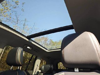 Панорамная крыша Ford Equator: стеклянный люк в крыше, через который видно небо и верхнюю часть салона с подголовниками на переднем плане.