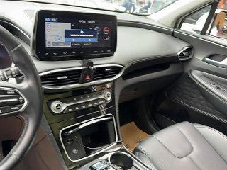 Центральная консоль и экран мультимедиа Hyundai Santa Fe: сенсорный дисплей навигации, кнопки управления климатом и декоративная отделка приборной панели.