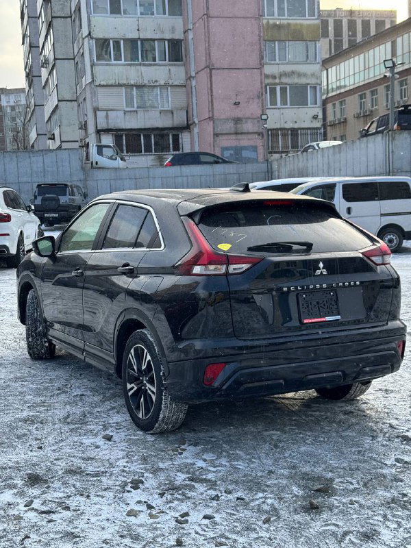 Задняя часть чёрного Mitsubishi Eclipse Cross 2023 на снежной стоянке; вид сзади с акцентом на дизайн фонарей и багажник, для клиента из Владивостока.