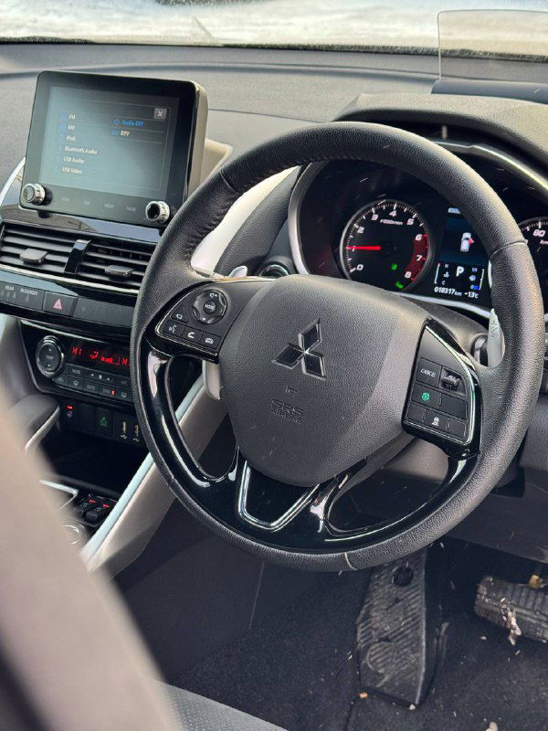 Салон и рулевое колесо Mitsubishi Eclipse Cross 2023, крупный план панели приборов и мультимедиа; фото показывает состояние салона и эргономику руля.