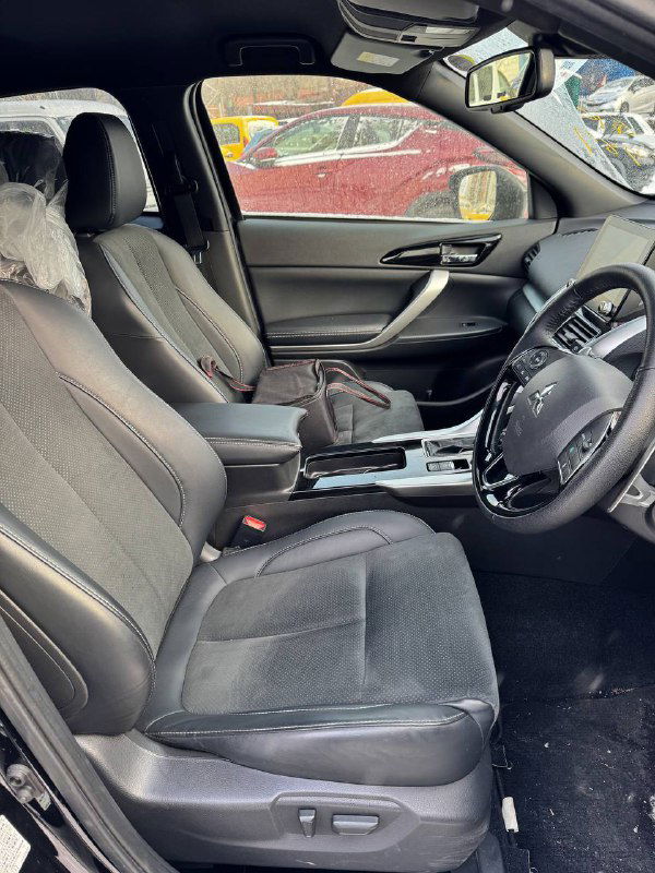 Передние сиденья и интерьер Mitsubishi Eclipse Cross 2023, вид сбоку; фото показывает обивку сидений, состояние и пространство в салоне для пассажиров.