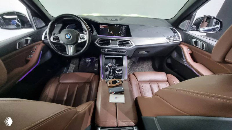 Вид на переднюю часть салона BMW X5 M-Sport: руль, центральная консоль и приборная панель, коричневая кожа.