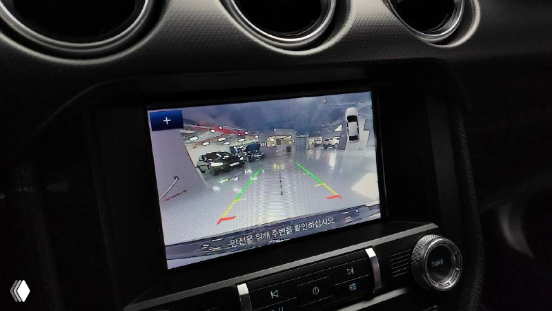 Крупный план мультимедийного экрана Ford Mustang Coupe: изображение с камеры заднего вида и интерфейс парктроника на центральной консоли.