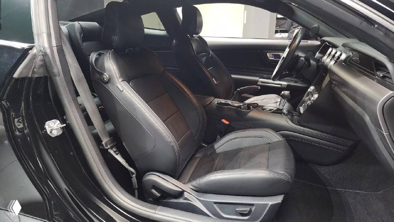 Передние сиденья Ford Mustang Coupe 2021 в чёрной коже — боковая поддержка, элементы регулировки и состояние обивки на ближнем плане.
