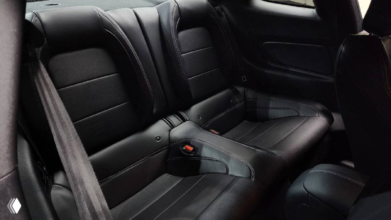 Задние сиденья Ford Mustang Coupe 2021 — два посадочных места, чёрная отделка, вид на центральный подлокотник и состояние обивки.