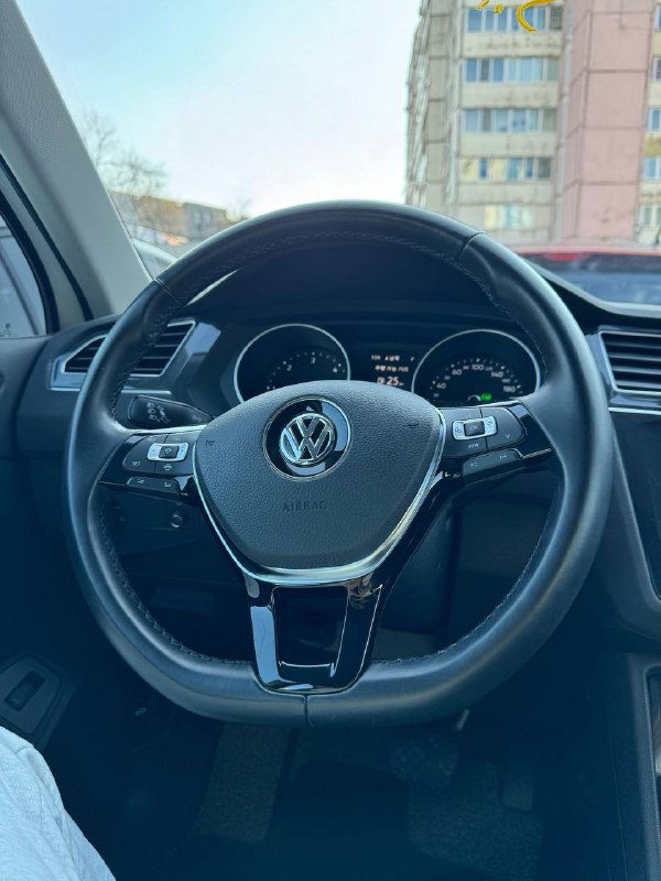 Крупный план руля Volkswagen Tiguan 2020 с логотипом; вид приборной панели и мультируля, интерьер в оригинальной отделке.