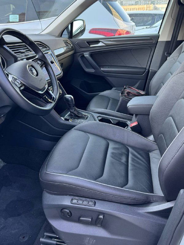 Переднее пассажирское сиденье и водительская зона Volkswagen Tiguan 2020 — общий вид салона, обивка и состояние кресел перед отправкой.