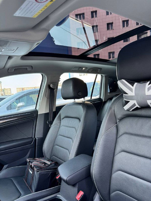 Панорамная крыша и передняя часть салона Tiguan: вид на потолок, передние сиденья и интерьер через стеклянный люк панорамы.