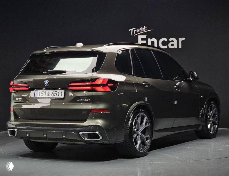 Фото BMW X5 xDrive 40i M Sport сзади в шоуруме; видны задние фонари, бампер и часть салона через стекла, автомобиль на парковке.