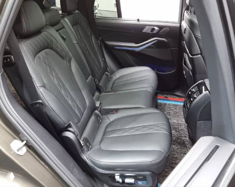 Изображение заднего ряда сидений BMW X5: кожа, пространство для ног и общий вид салона с кормовой части, подчёркнута комфортная посадка.
