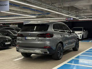 Кадр BMW X5 xDrive 50e xLine сзади на подземной парковке; видны задние фонари, бампер и общая линия кузова гибридной модели.
