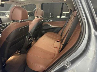 Изображение задних сидений BMW X5 xDrive 50e xLine с коричневой обивкой; демонстрируется комфорт, подлокотник и пространство для пассажиров.
