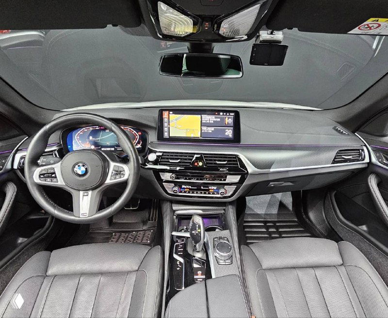 Интерьер BMW 520i M Sport: панель приборов, мультимедийный экран по центру и спортивный трёхспицевый руль с подчёркнутыми элементами управления.
