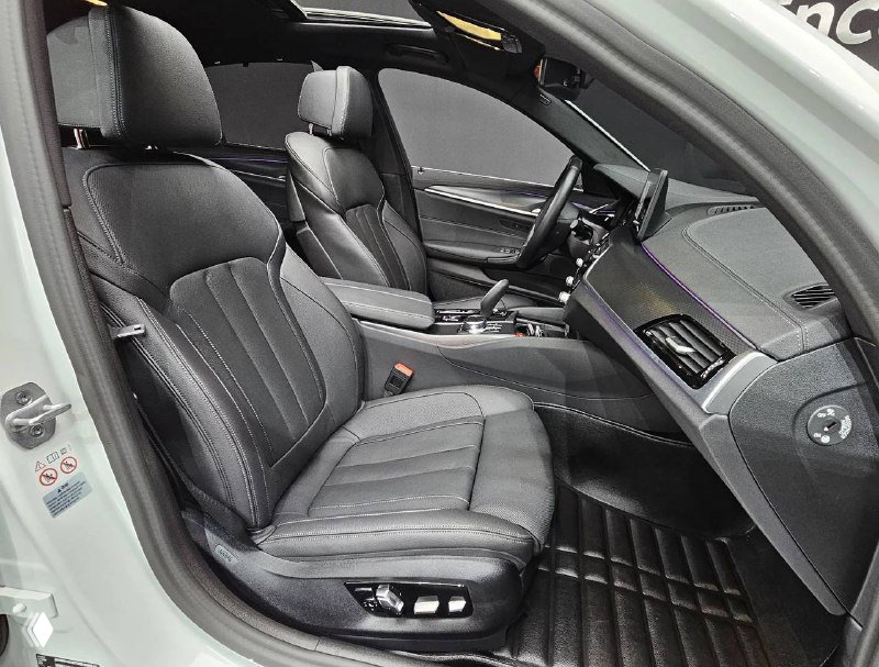 Фотография переднего кресла и центральной консоли BMW 520i M Sport: кожаная обивка, регулировки сиденья и селектор коробки передач.