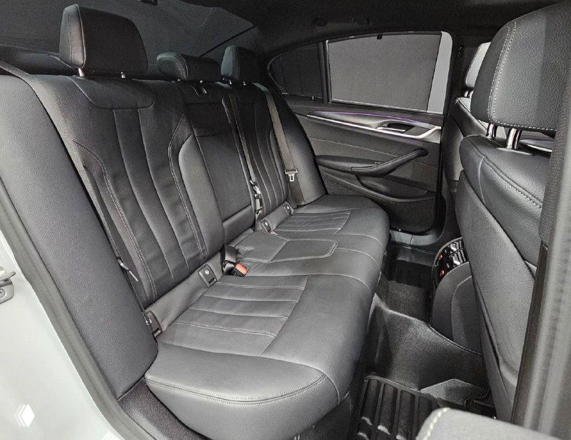 Задний ряд сидений BMW 520i M Sport: кожаная обивка, просторный салон и детализированные прострочки сидений на тёмном фоне.