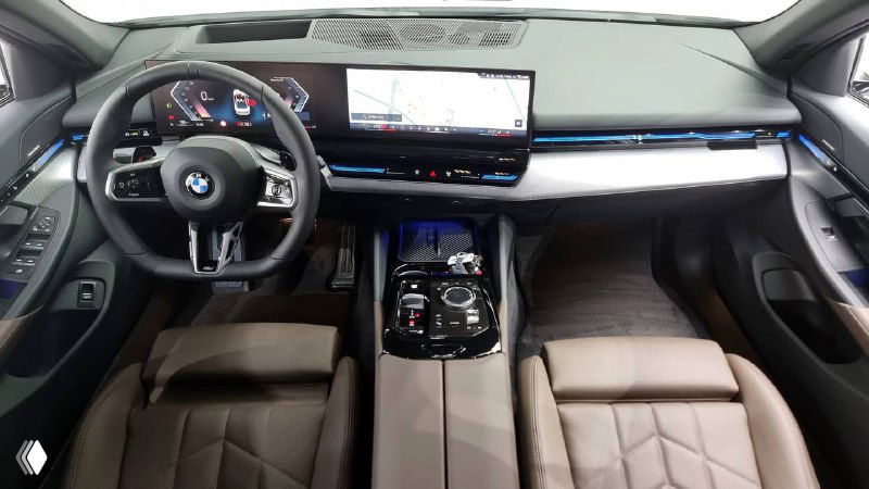 Снимок салона BMW 520i M Sport с центральной консолью и рулём — обзор приборной панели, мультимедиа и отделки кожей, интерьерный ракурс.