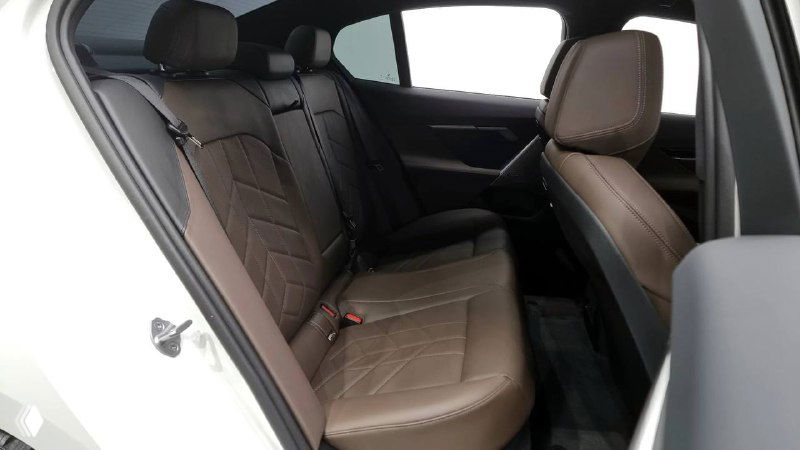 Снимок заднего ряда сидений BMW 520i M Sport — коричневая кожаная обивка, три посадочных места, ремни безопасности и пространство для ног.