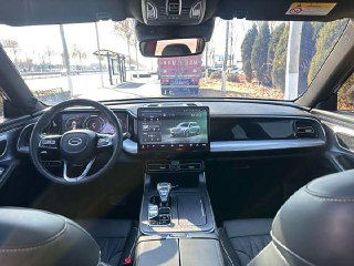 Широкий обзор центральной консоли GAC Trumpchi GS8, крупный сенсорный дисплей, селектор коробки передач и обивка салона — интерьер в аккуратном состоянии.