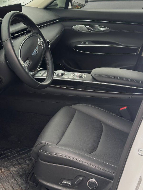 Панорамный вид передней части салона Genesis GV70: руль, панель приборов, центральная консоль и передние сиденья.