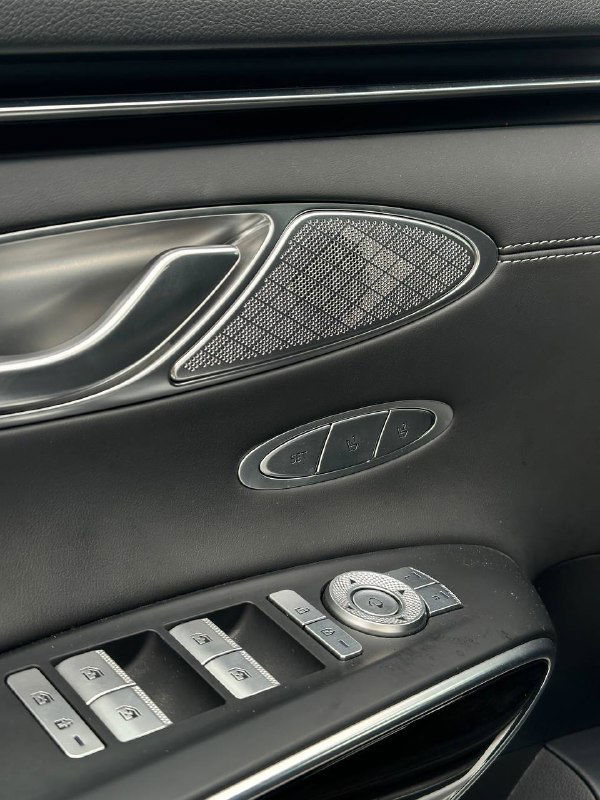 Дверная панель Genesis GV70 с динамиком, кнопками стеклоподъёма и декоративной отделкой — детальный ракурс интерьера.