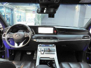 Фотография салона Hyundai Palisade с видом на панель приборов и большой экран мультимедиа, интерьер в тёмных тонах, обзор приборной панели.