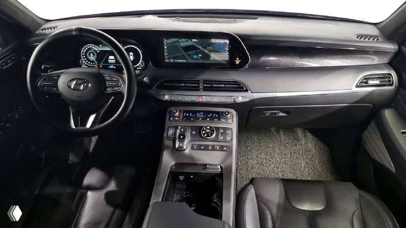 Фотография приборной панели и центральной консоли Hyundai Palisade: экран, селектор управления и элементы климата в тёмном салоне.