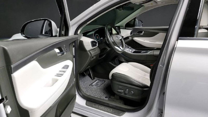 Фрагмент водительской стороны салона Hyundai Santa Fe, открытая дверь и кресло водителя; снимок для демонстрации кресел и пространства внутри автомобиля.