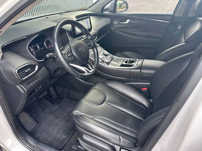 Крупный план рулевого колеса и приборной панели Hyundai Santa Fe, снимок показывает состояние руля, подрулевые элементы и общую эргономику салона.