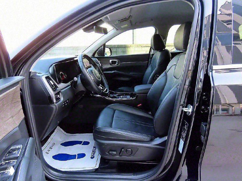 Переднее сиденье и водительская зона KIA Sorento 2021, вид с открытой двери; показаны кресла, консоль и напольные коврики.