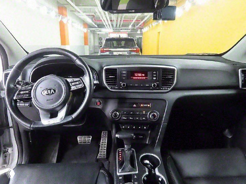 Салон KIA Sportage 2021: вид на руль, центральную консоль и приборную панель с мультимедийной системой и климат‑контролем.