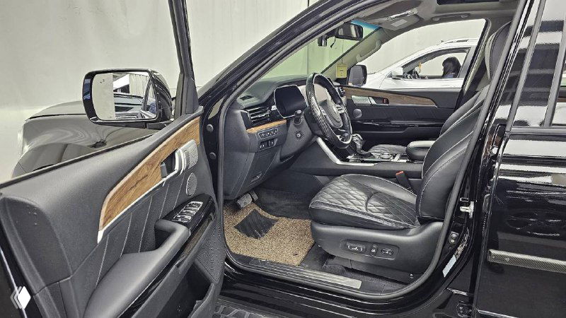 Открытая передняя дверь KIA Mohave 2020: вид на кресло водителя, боковую панель и элементы управления с деревянной отделкой.