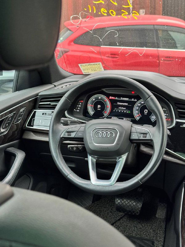 Вид рулевого колеса и передней панели Audi Q8: мультируль, цифровая приборная панель и часть лобового стекла с наклейками.