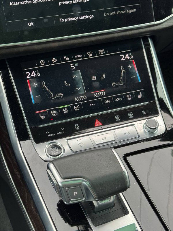 Крупный план селектора КПП и нижней сенсорной панели климата в Audi Q8, показаны элементы управления обогревом и кондиционированием.