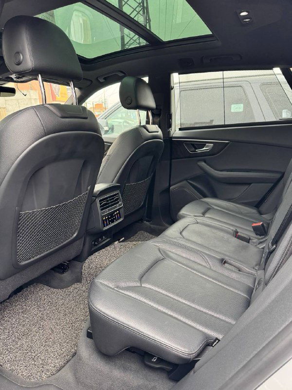 Задние сиденья Audi Q8: чёрная кожа, подголовники и простор для ног на фото, видна центральная консоль с вентиляционными решётками.