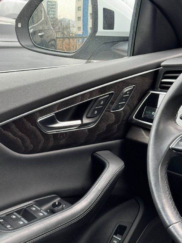 Деталь дверной обшивки Audi Q8: элементы управления сиденьями, декоративная вставка под карбон/дерево и кнопки стеклоподъёмников.