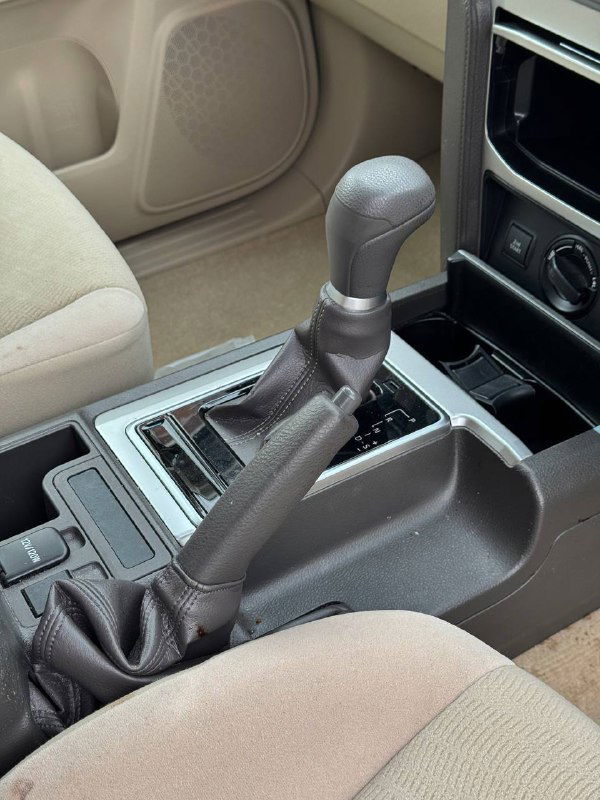 Рычаг переключения передач и ручной тормоз Toyota Prado в центральной зоне салона, вид на селектор коробки и окантовку консоли