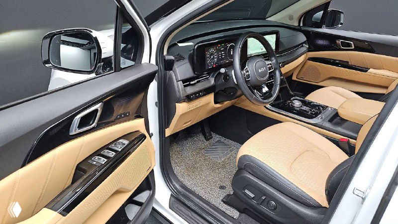 Водительская дверь и переднее сиденье KIA Carnival Signature 2021 — элементы управления, кожа бежевого цвета и панель приборов в хорошем состоянии.