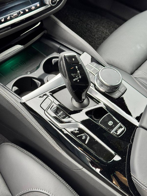 Селектор коробки передач, контроллер iDrive и блок кнопок на центральном тоннеле BMW — крупный план, подчёркивает аккуратность и износ элементов