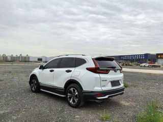 Задний ракурс белой Honda CR‑V на гравийной площадке в Китае, вид сзади-справа; видно заднюю часть кузова и окрестности стоянки.