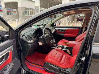 Вид на водительскую дверь и панель управления чёрной Honda CR‑V: сиденье, дверная карта и элементы управления на фоне красной обивки.