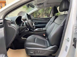 Переднее сиденье и боковая панель Hyundai Tucson 2022: чёрная отделка сидений, регулировки положения и часть дверной обшивки видны крупным планом.