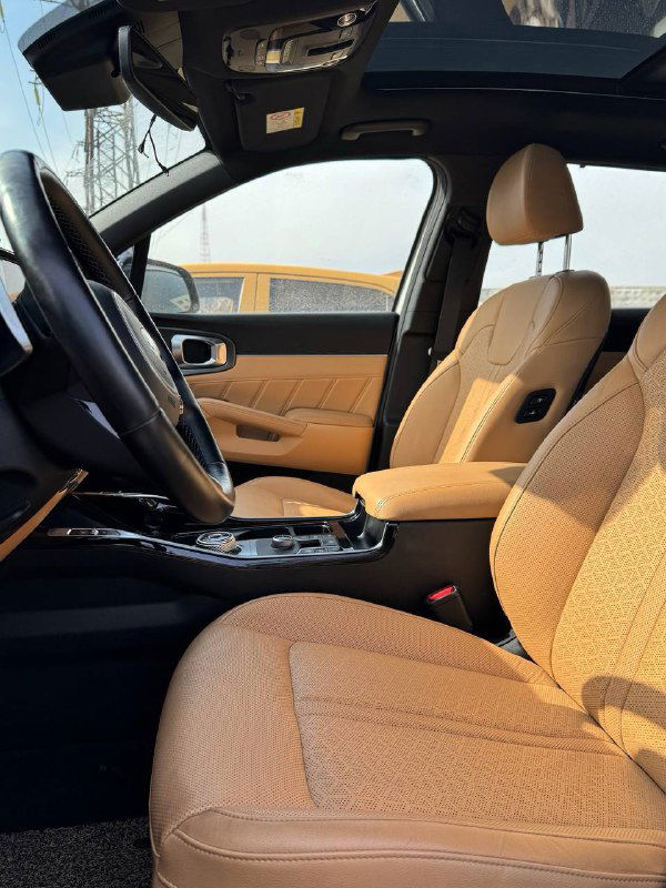 Вид на передние сиденья KIA Sorento в коричнево‑оранжевой коже; панорамная крыша и интерьер со стороны пассажирского места.