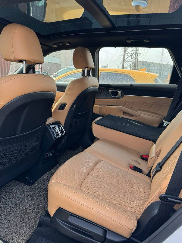 Задний ряд сидений KIA Sorento: простор для ног, отдельные подлокотники и коричнево‑оранжевая кожаная обивка для пассажиров.