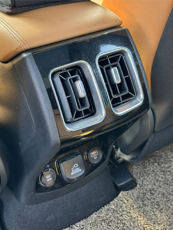 Воздуховоды и элементы управления климатом на задней консоли, розетки и разъёмы; видно оформление и функциональные элементы для пассажиров сзади.