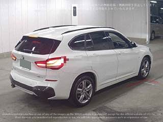 Белый BMW X1 (2020) — вид сзади на площадке аукциона в Японии; отчетливые фонари, бампер и общий профиль кузова лота.