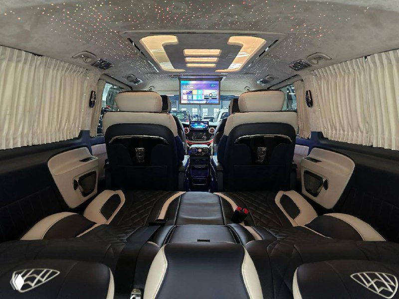 Вид из задней части салона Mercedes Vito на капитанские кресла и центральный проход, демонстрирующий простор и мультимедийные экраны.