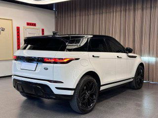 Обзор задней части белого Range Rover в шоуруме: задние фонари, бампер и диффузор видны на контрастном фоне занавесок