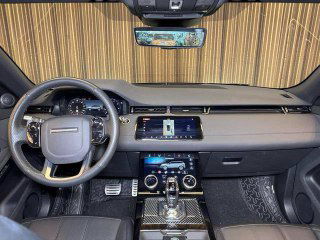 Салон Range Rover: вид на руль, приборную панель и центральную консоль с экраном мультимедиа; чёрная отделка и премиальные материалы видны крупно