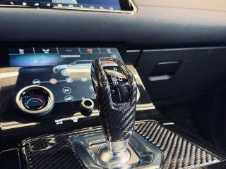 Рычаг переключения передач Range Rover с декоративными элементами под карбон и крупный план деталей отделки на центральной консоли
